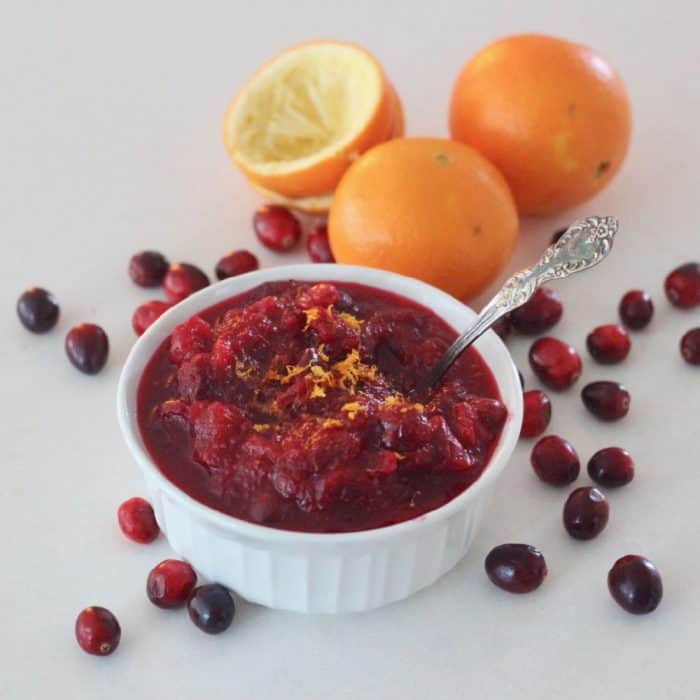 white bowl of Cranberry Sauce with oranges and fresh cranberries