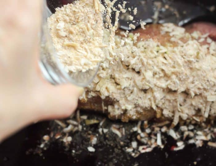 sprinkling spices onto pork tenderloin in slow cooker
