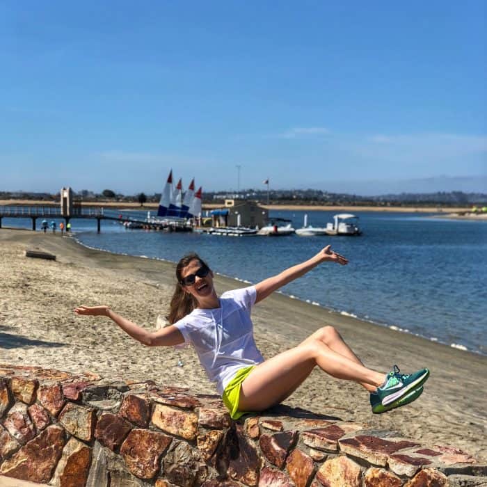 girl sitting on brick wall in front of Mission Bay