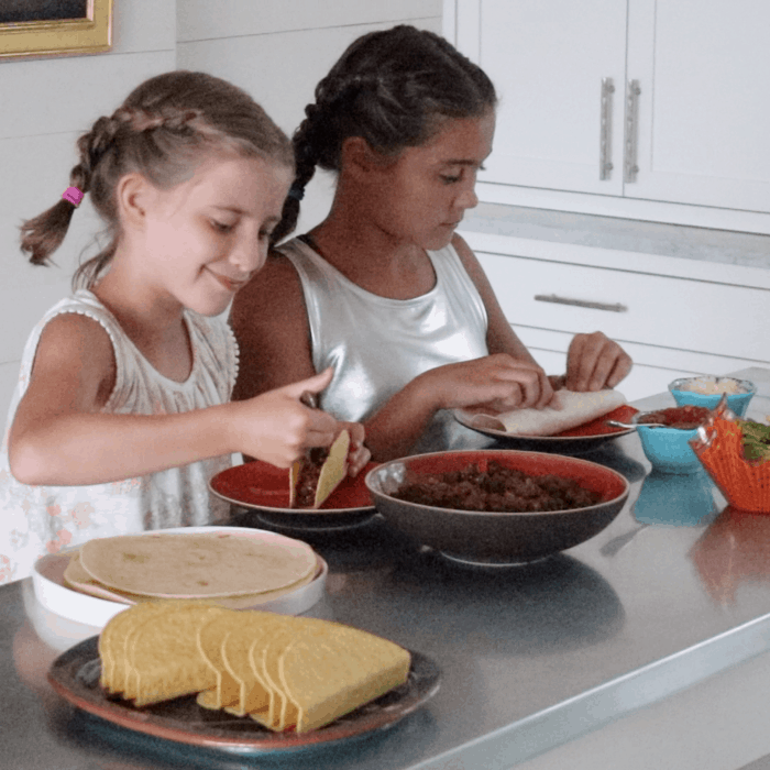 two young girls preparing tacos