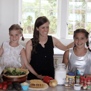 Two girls and an adult cooking tacos