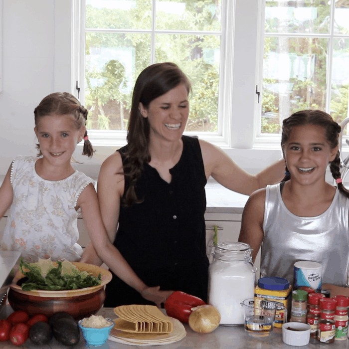 Two girls and an adult cooking tacos