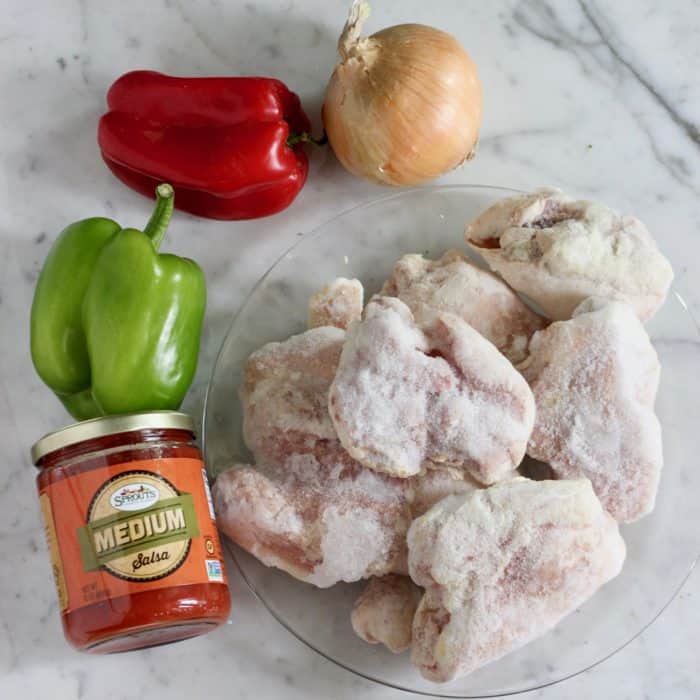 plate of frozen chicken, jar of salsa, green and red bell pepper, onion