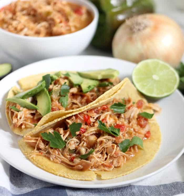 salsa chicken in tortillas with parsley, sliced avocados, and lime