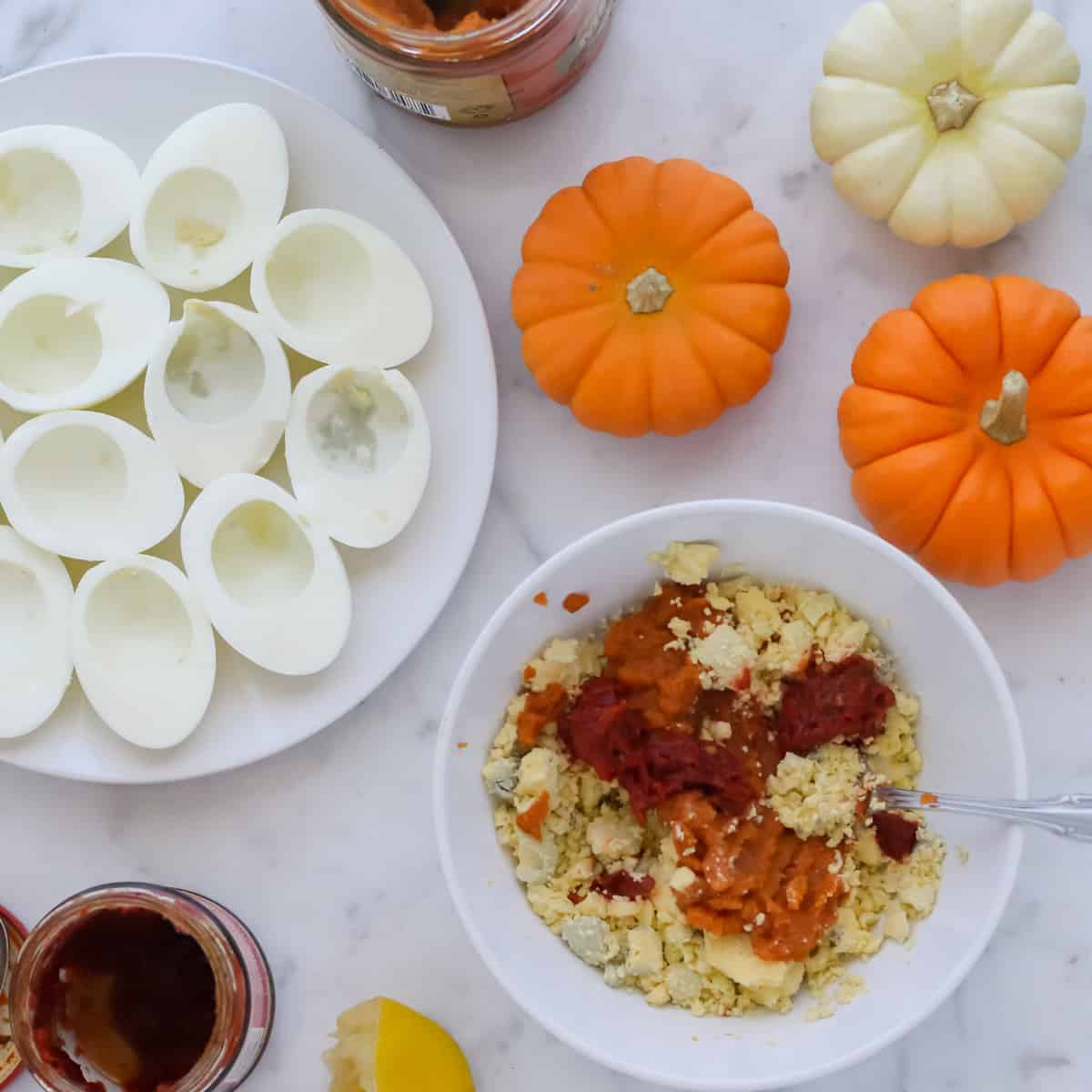 plate of egg whites with a bowl of yolks, pumpkin, and harissa paste next to a plate of egg whites