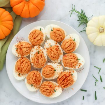 kitchen counter with small orange and white pumpkins plus a white plate with pumpkin deviled eggs
