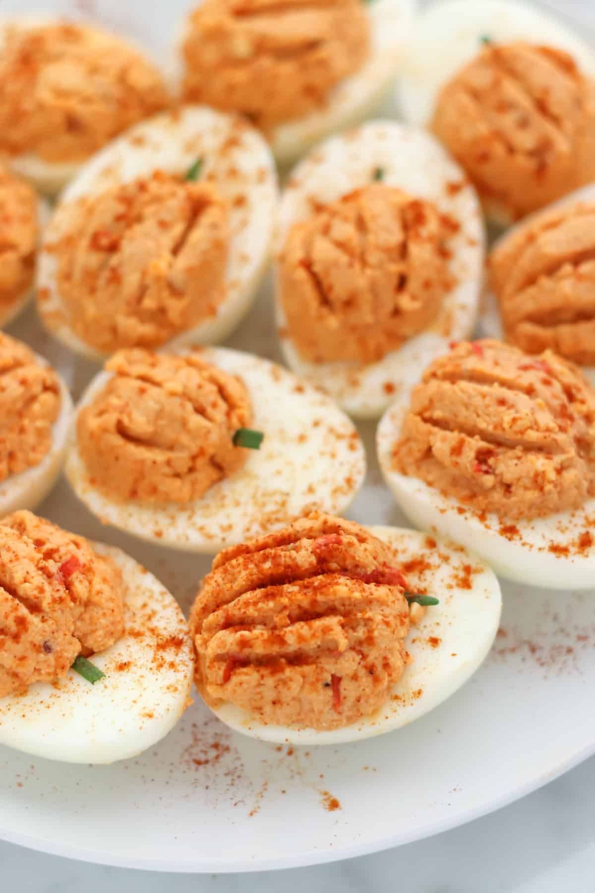 white plate with pumpkin deviled eggs sprinkled in paprika