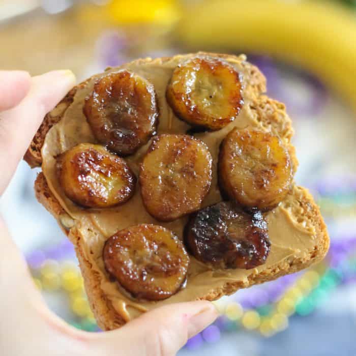 hand holding sliced cooked bananas on peanut butter toast