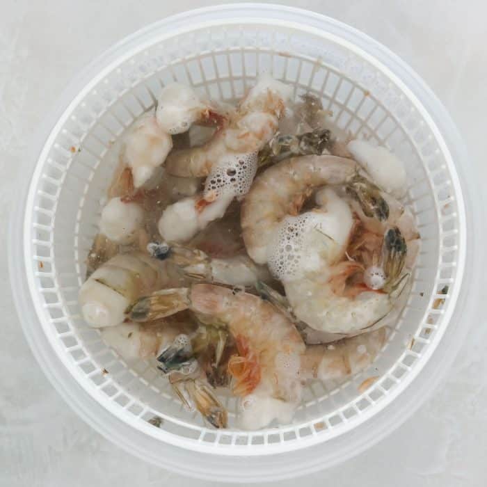 plastic bowl with frozen shrimp thawing