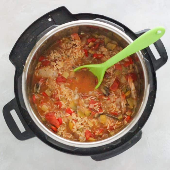 instant pot with cooked jambalaya and green spoon