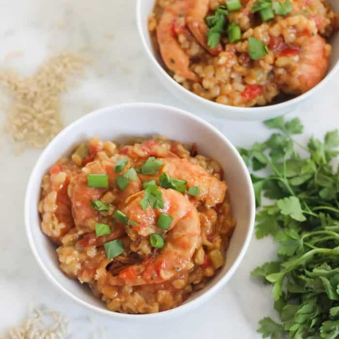 two bowls of shrimp jambalaya with rice and parsley
