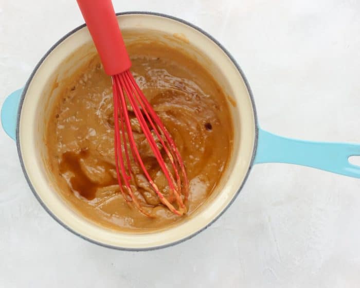 whisk stirring together cashew butter, honey, salt, vanilla extract in blue saucepan