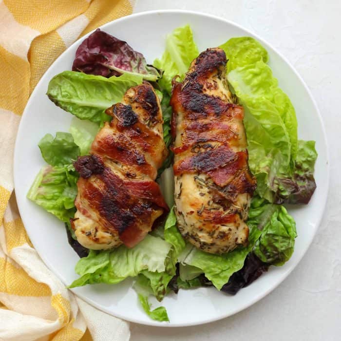 two pieces of bacon wrapped chicken breast over lettuce