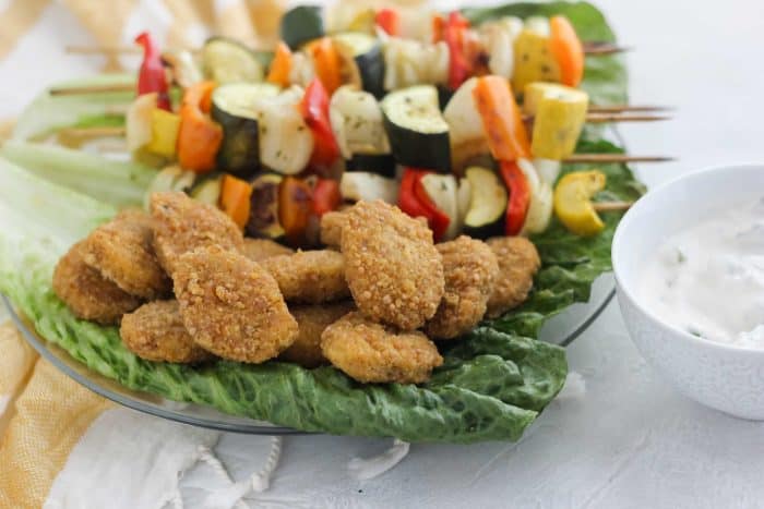 chicken nuggets and vegetable kabobs on green leaf lettuce