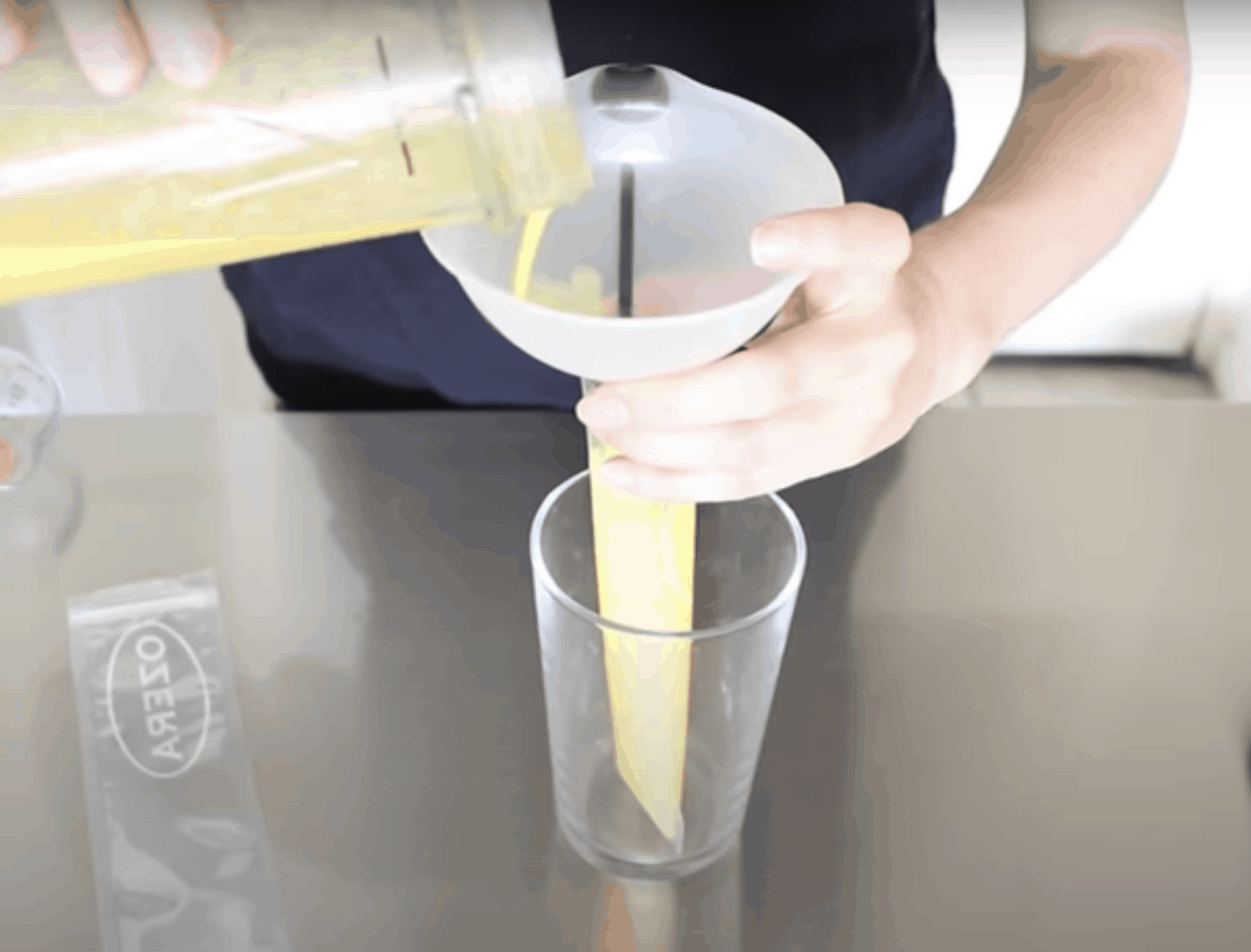 hand pouring mixture through a funnel into a popsicle bag