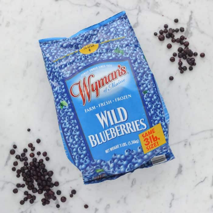 bag of frozen Wyman's Wild Blueberries on marble counter with some blueberries scattered around