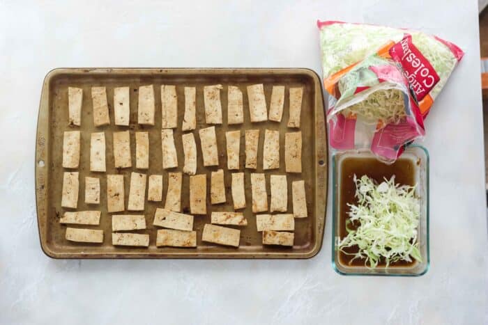 tofu on a baking sheet, bag of coleslaw, coleslaw in marinade