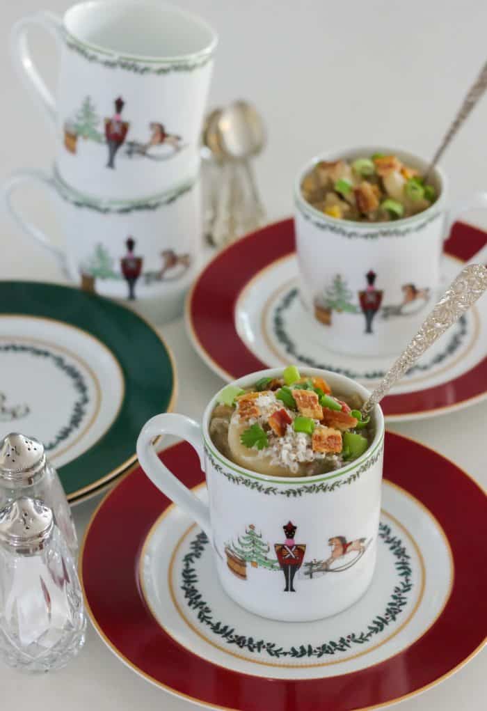 cheeseburger soup in Christmas bowls topped with bacon, green onions and cheddar on red and green plates