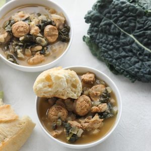 white bowls with sausage kale soup with french bread and fresh kale