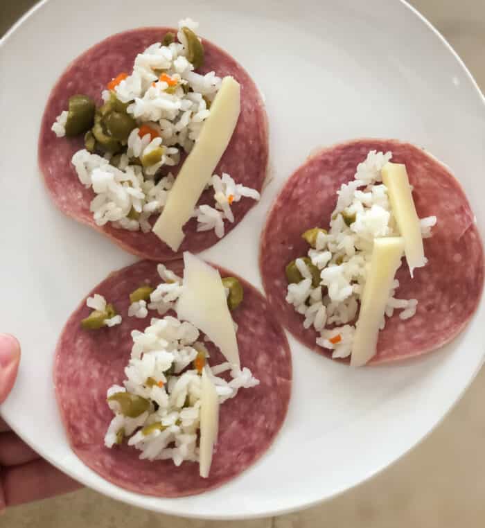 plate with beef salami topped with rice, capers, olives, and cheese
