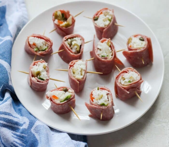 plate of beef sushi with toothpicks on a white table with a blue napkin