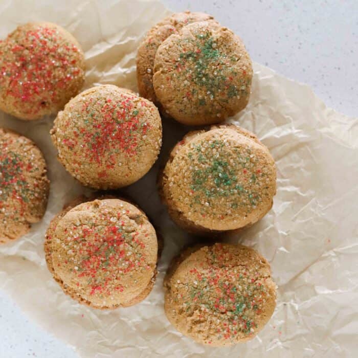stacks of ginger cookies made without molasses with green and red sprinkles sitting on crinkled parchment paper