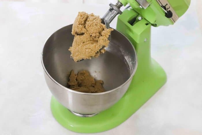 green stand mixer with mixing paddle full of gingersnap cookie dough