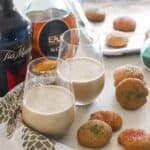 two wine glasses with coffee ice cream drinks, bottles of brandy and Tia Maria, on white and gold napkins, with Christmas cookies