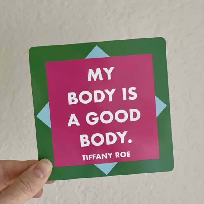 hand holding a green affirmation card that reads "my body is a good body. Tiffany Roe"