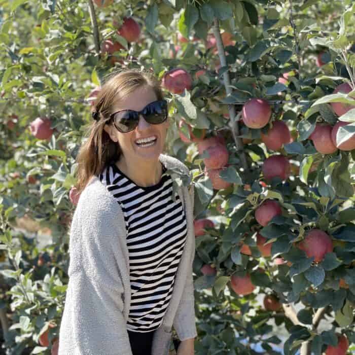 brunette female smiling in front of apple trees