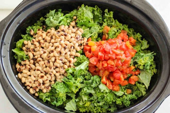 black eyed peas, diced tomatoes, and kale in a black slow cooker