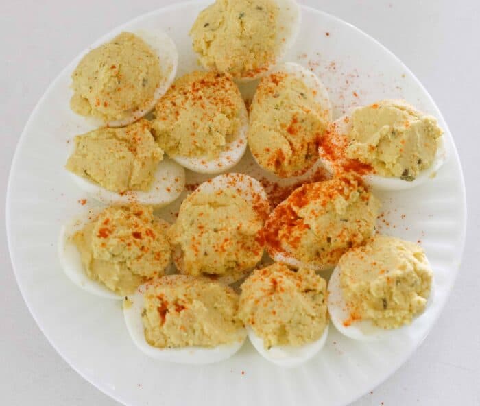 white plate with deviled eggs sprinkled with paprika