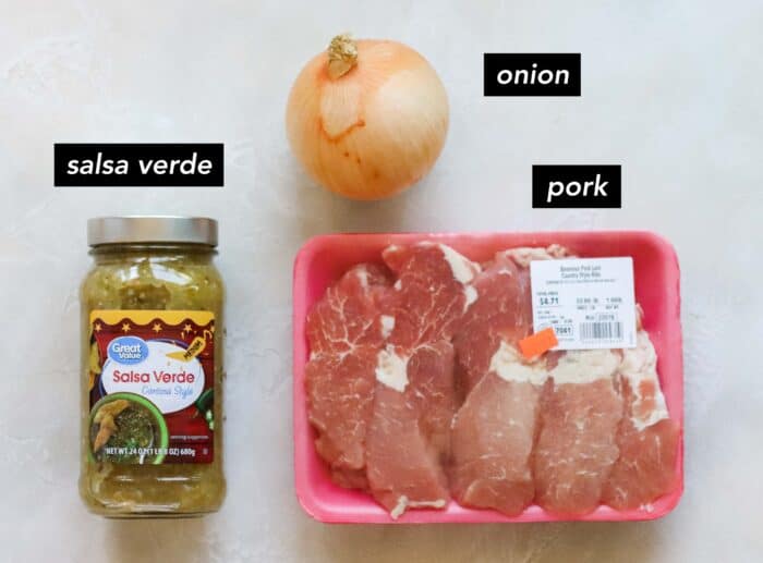 jar of salsa verde, yellow onion, and a container with pork loin ribs on a white counter with text overlay describing ingredients