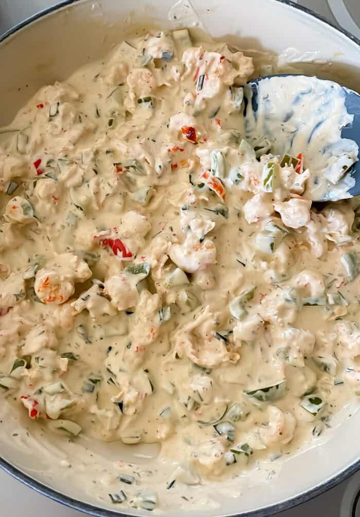 crawfish dip in a blue braiser with grey spatula