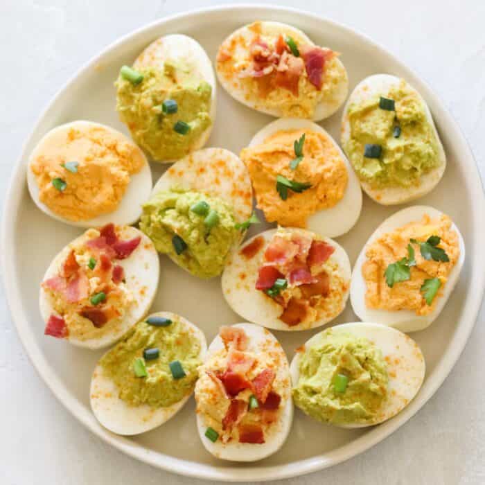 plate with hummus deviled eggs, bacon deviled eggs, and avocado deviled eggs