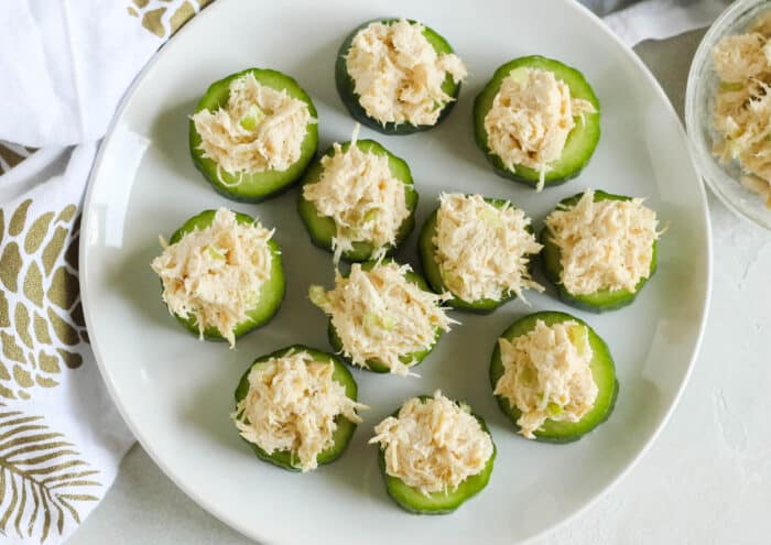 white plate with cucumber slices topped with chicken salad