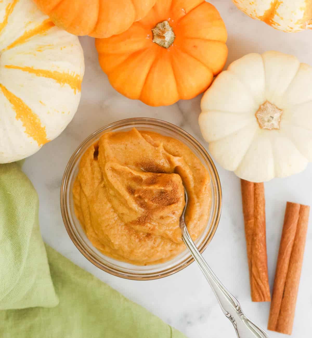 bowl of banana pumpkin ice cream with mini pumpkins and cinnamon sticks