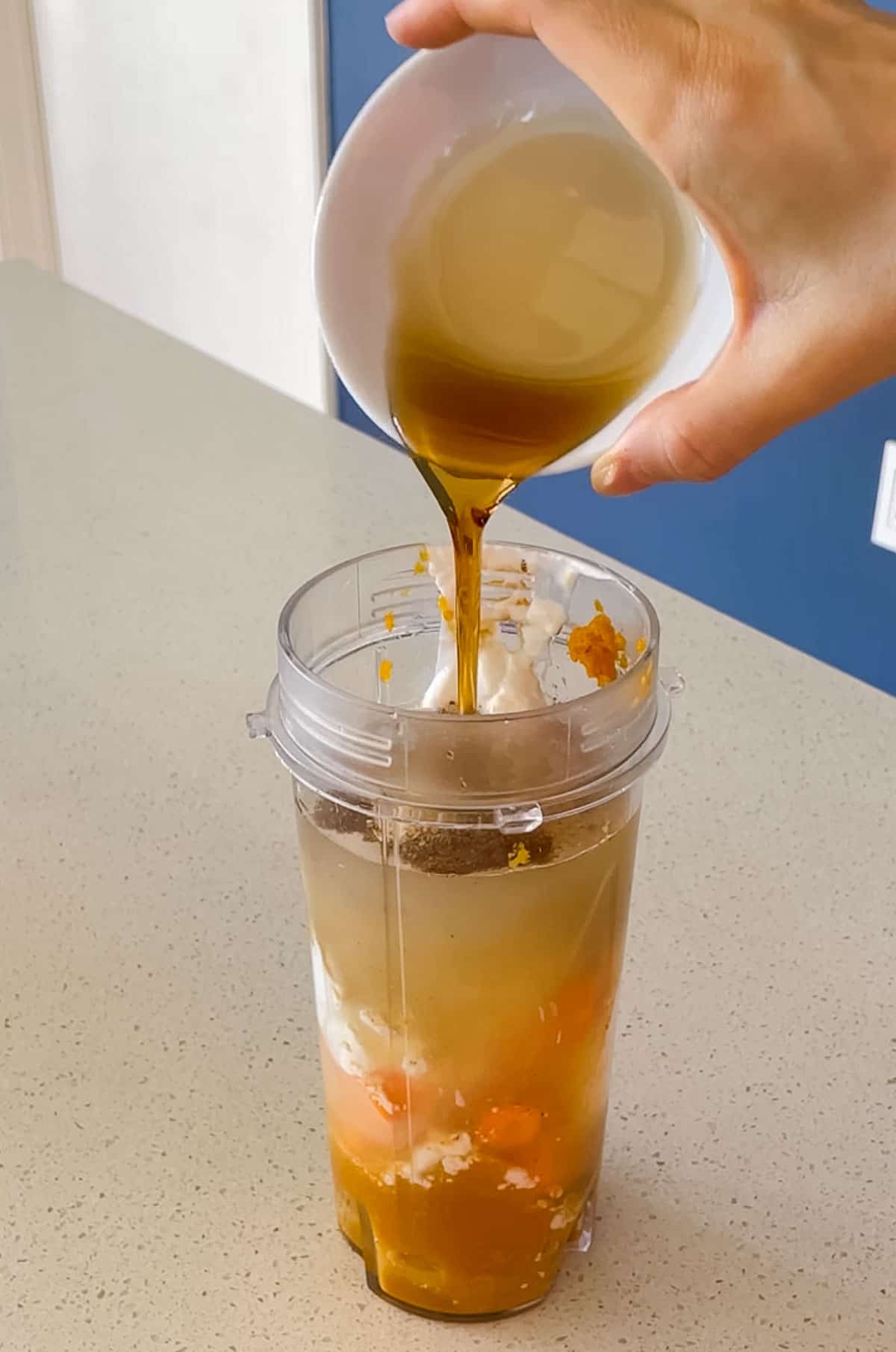 maple syrup being poured into a blender cup