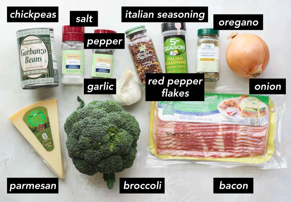 wedge of parmesan, head of broccoli, package of bacon, onion, jar of oregano, jar of italian seasoning, jar of crushed red pepper, head of garlic, peppercorn container, salt container, can of chickpeas