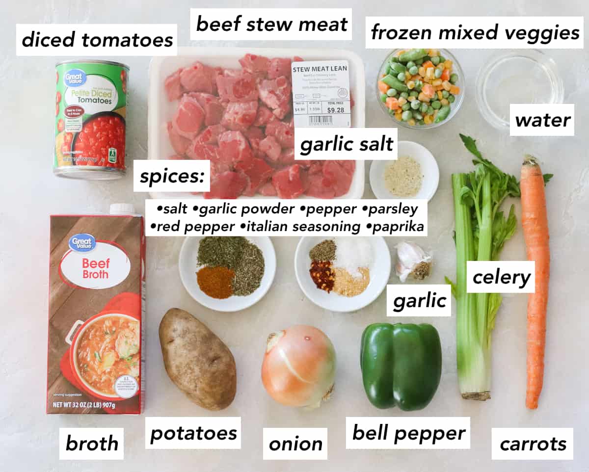 can of diced tomatoes, carton of beef broth, potato, onion, green bell pepper, garlic, celery, carrot, bowl of water, bowl of frozen mixed veggies, package of lean beef stew meat, bowls with spices: italian seasoning, oregano, and paprika plus salt, pepper, red pepper flakes, and garlic powder