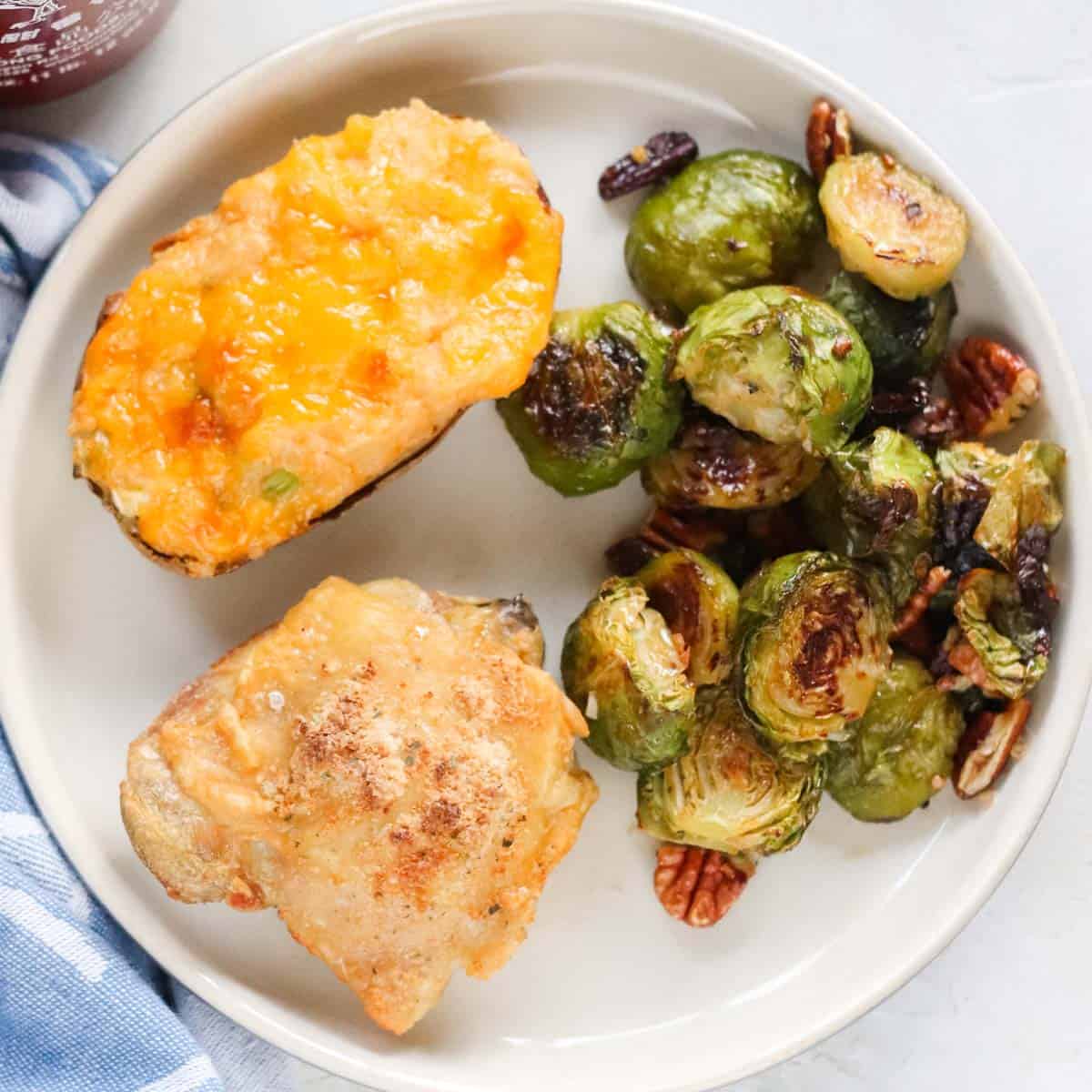 plate with twice baked potato, roasted Brussels sprouts, and a chicken thigh