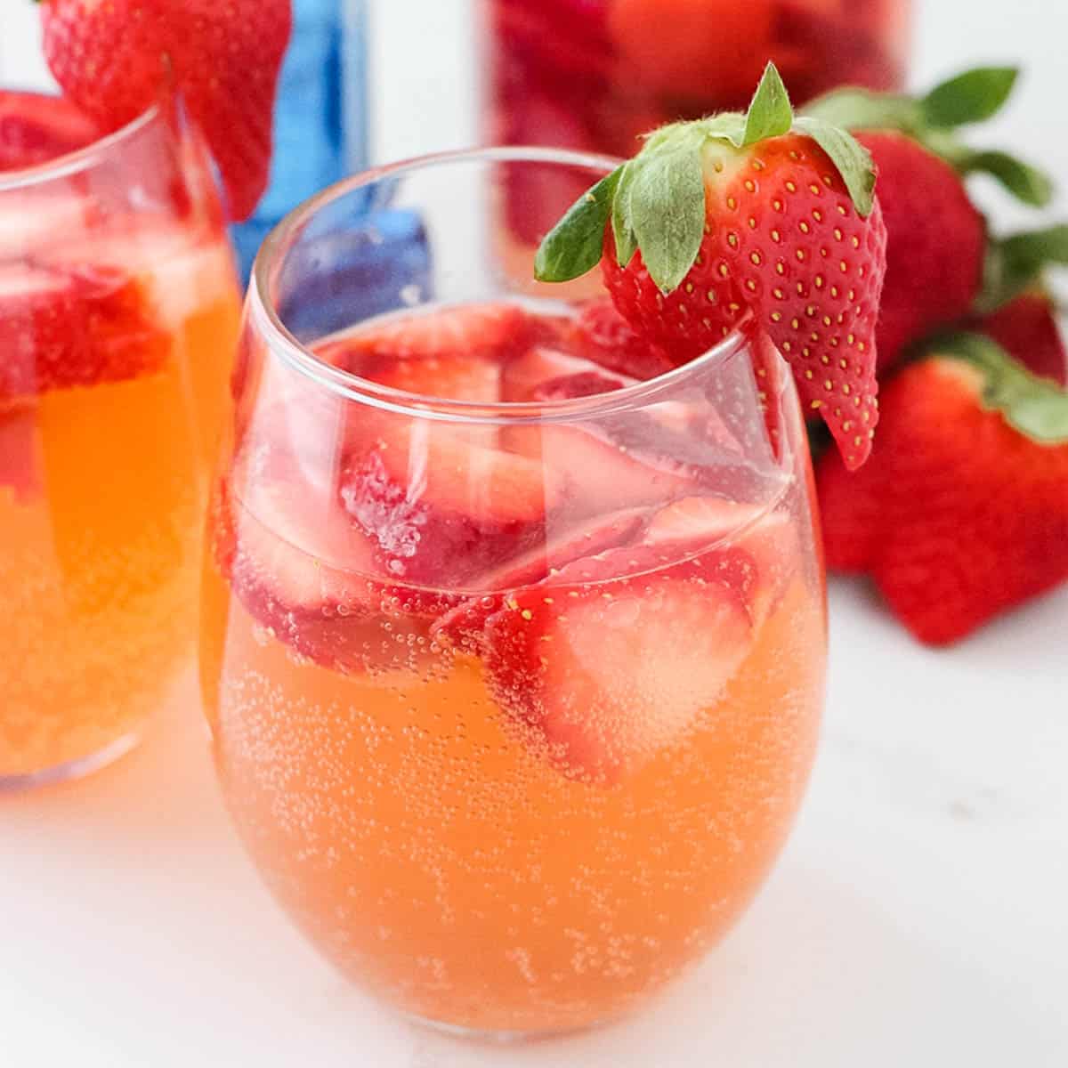 close up of a clear stemless wine glass with strawberry gin fizz with a fresh strawberry garnish
