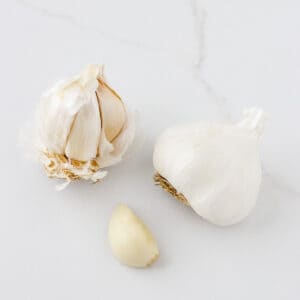 two heads of garlic next to one clove of garlic