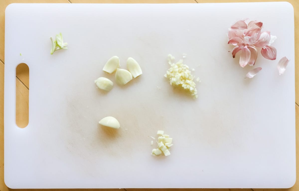 cutting board with whole, sliced, minced, and chopped garlic cloves plus garlic skins