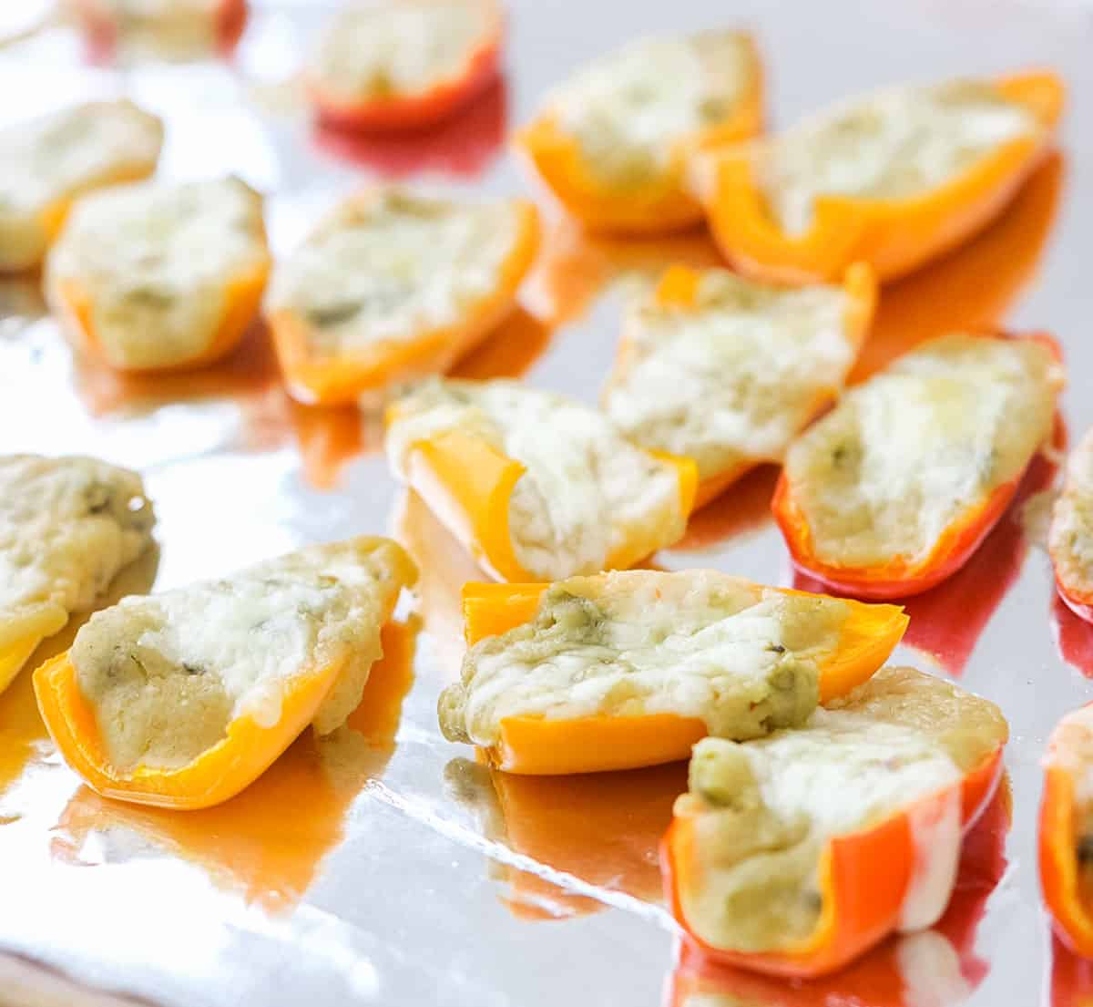 baked hummus stuffed peppers on a foil lined baking sheet