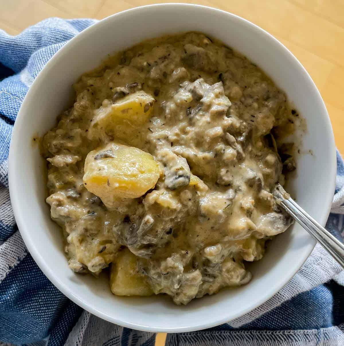 bowl of mushroom sausage hash mixed with cream cheese with a blue dish towel under it