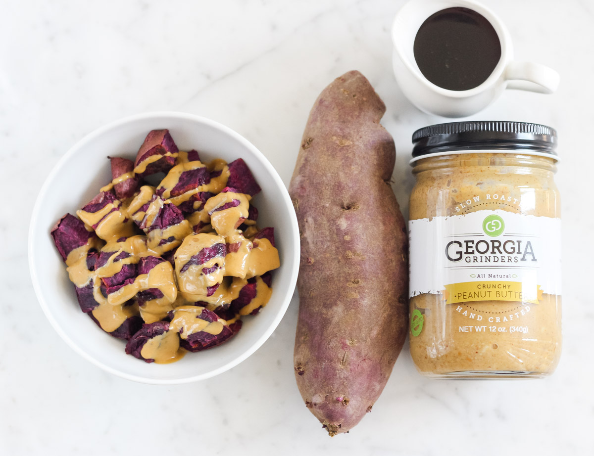 bowl of purple sweet potato covered in peanut butter next to a sweet potato and jar of peanut butter