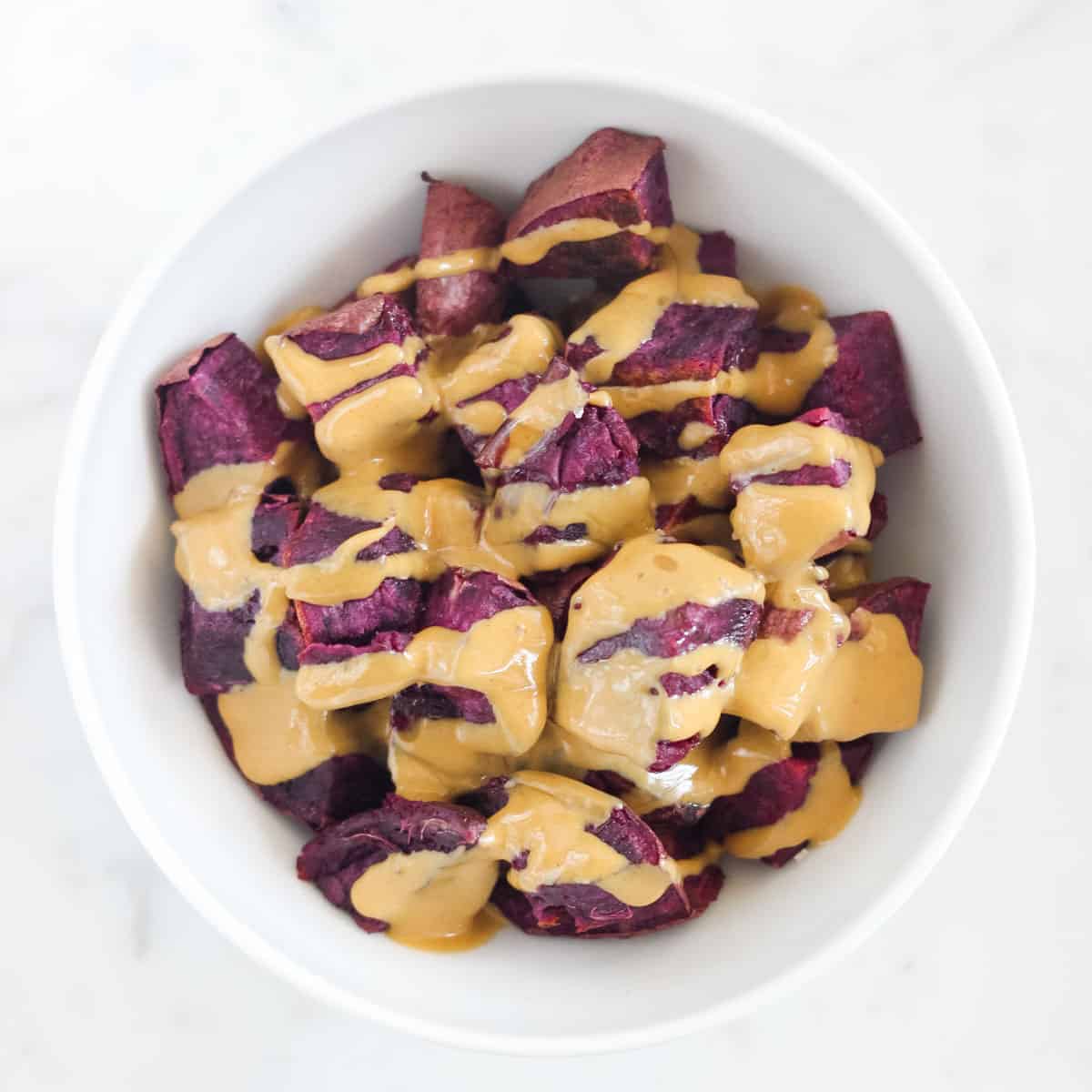 bowl with purple sweet potatoes covered in peanut butter