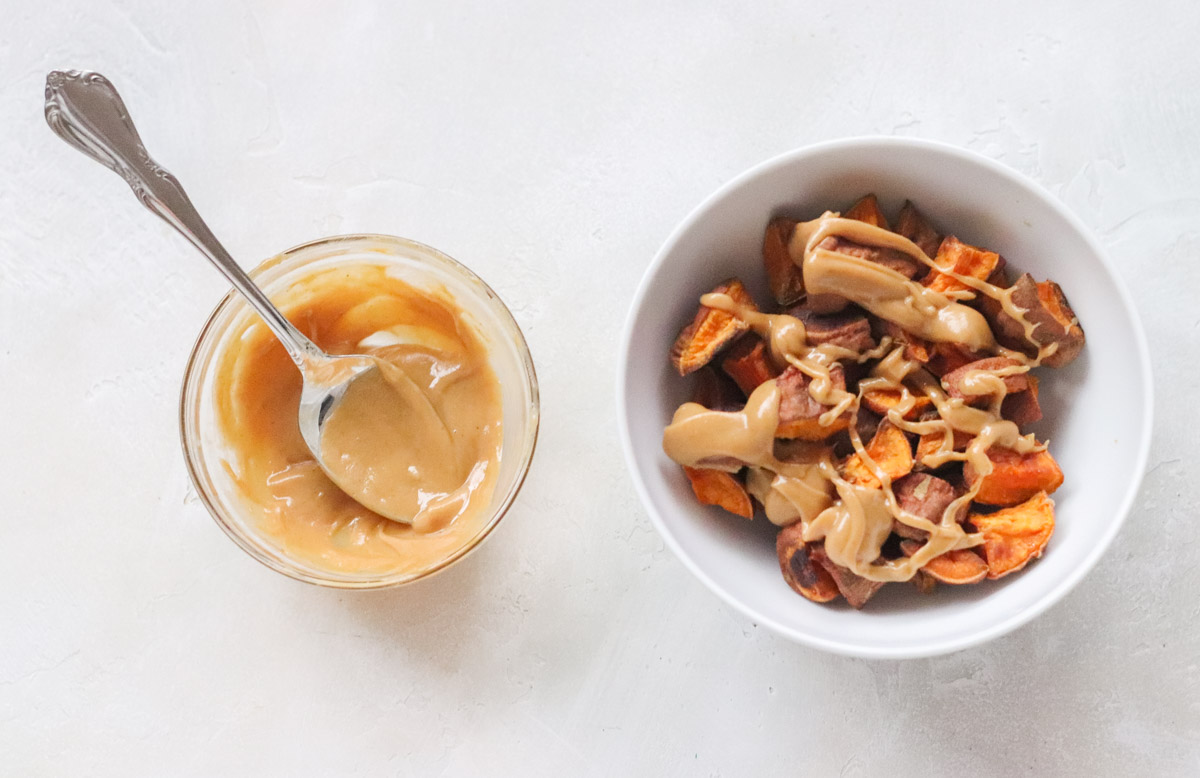 bowl of peanut butter and spoon next to a bowl of sweet potatoes drizzled with peanut butter