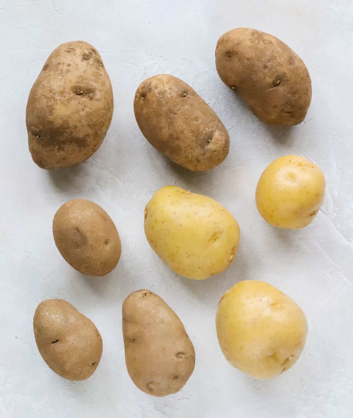 six russet potatoes and three yellow potatoes on a countertop